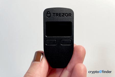 Image: Finder Trezor Model One held between fingertips